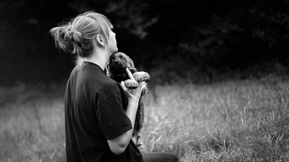 grayscale photo of person holding puppy