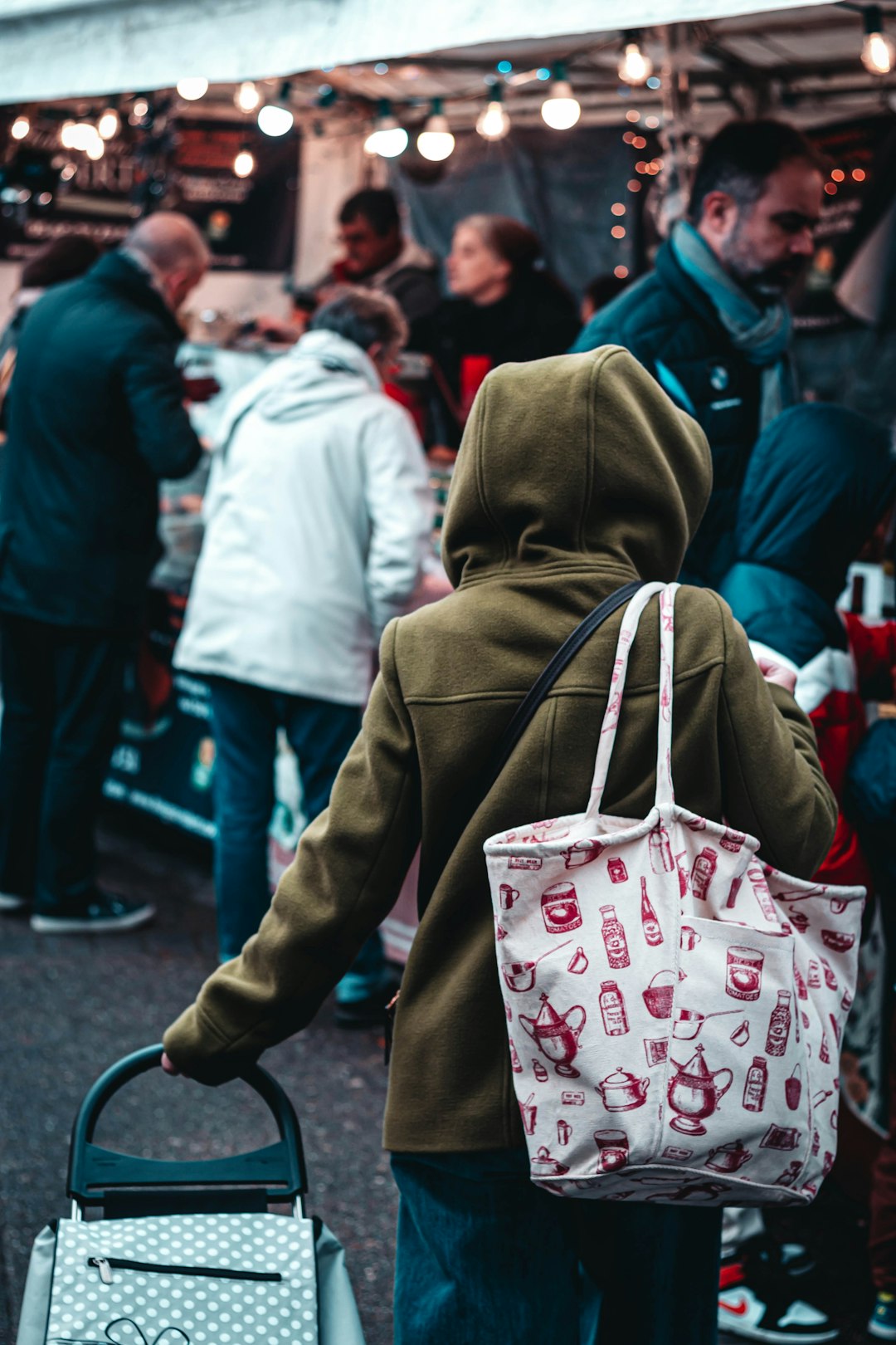 selective focus photo of woman carrying tote bag and cart