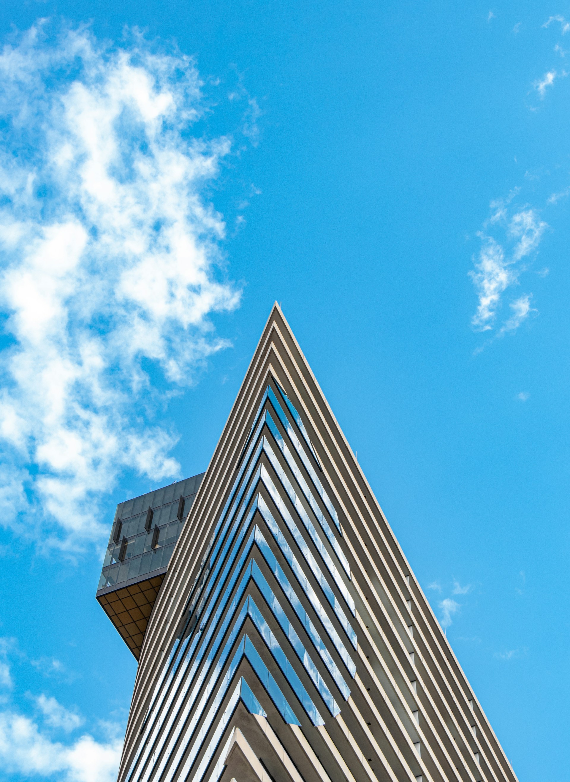 An exterior shot of a modern architectural tower with sharp angles against a clear sky.