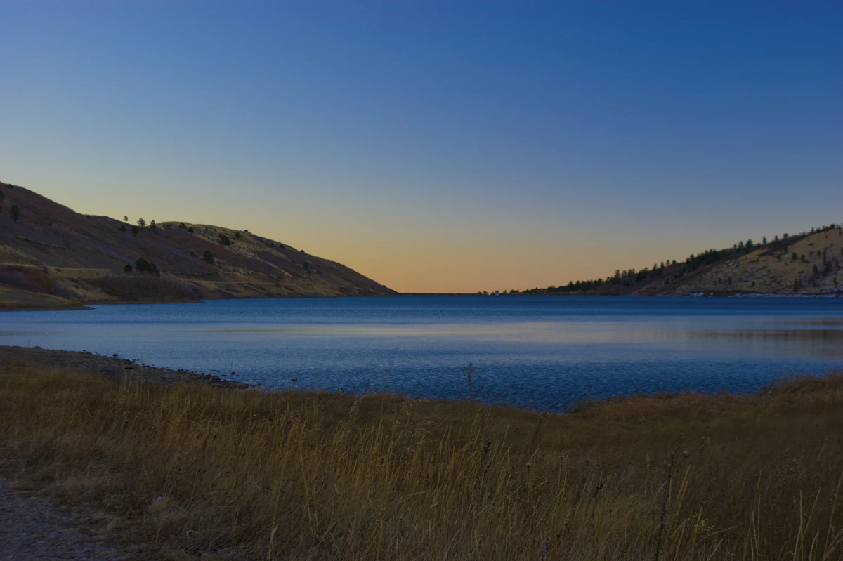 A lake below dry grassy hills at dusk, beside Colorado 12 near Trinidad