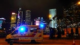 Ambulance parked outside a hospital with bright city lights in the background.
