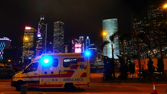 A dynamic cityscape at dusk with police cars and ambulances patrolling the streets.