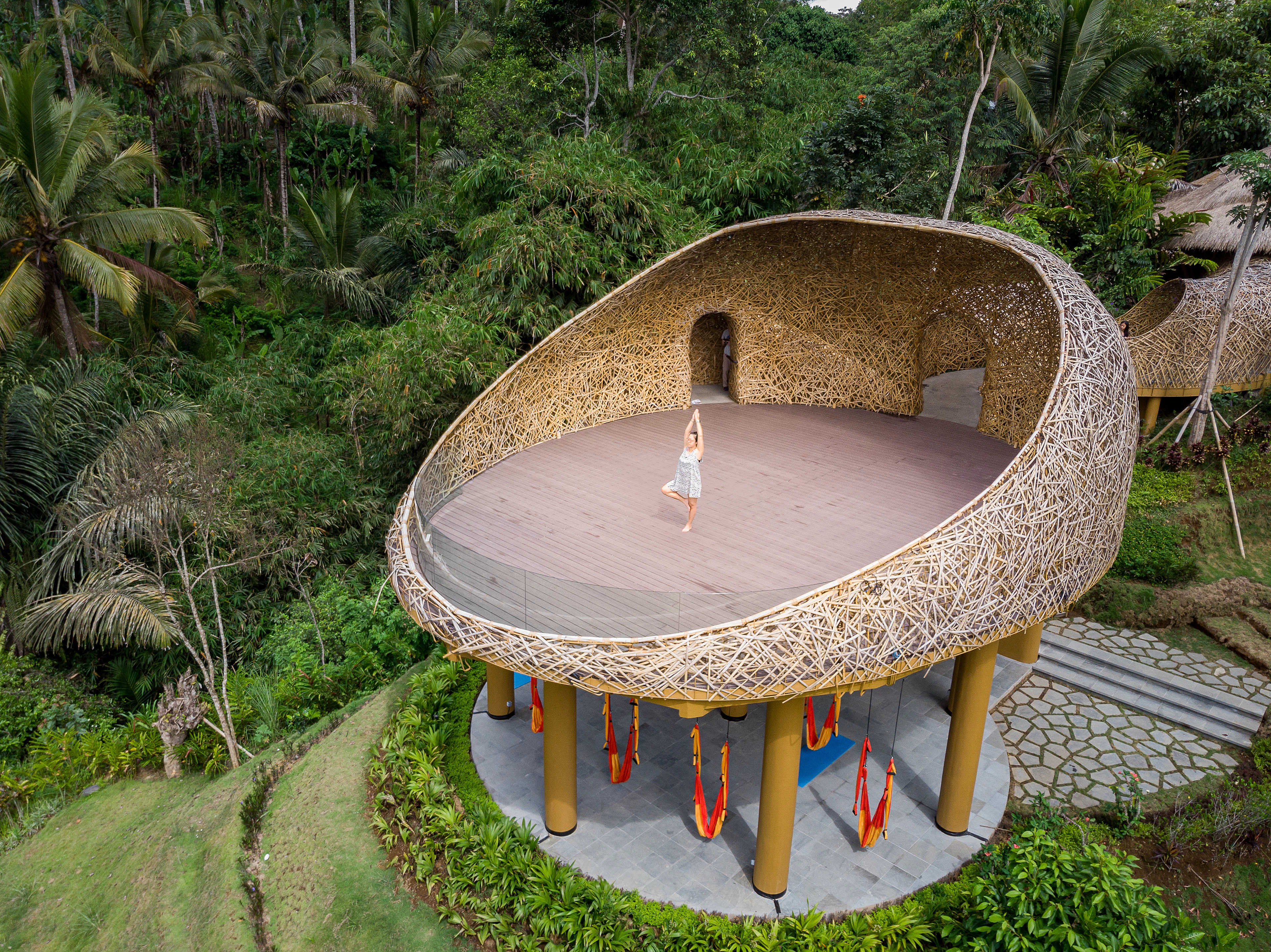 A woman standing on a woven nest among the trees in Ubud