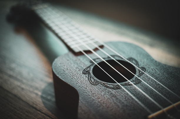 Close-up of hands strumming a ukulele with sunlight streaming in.