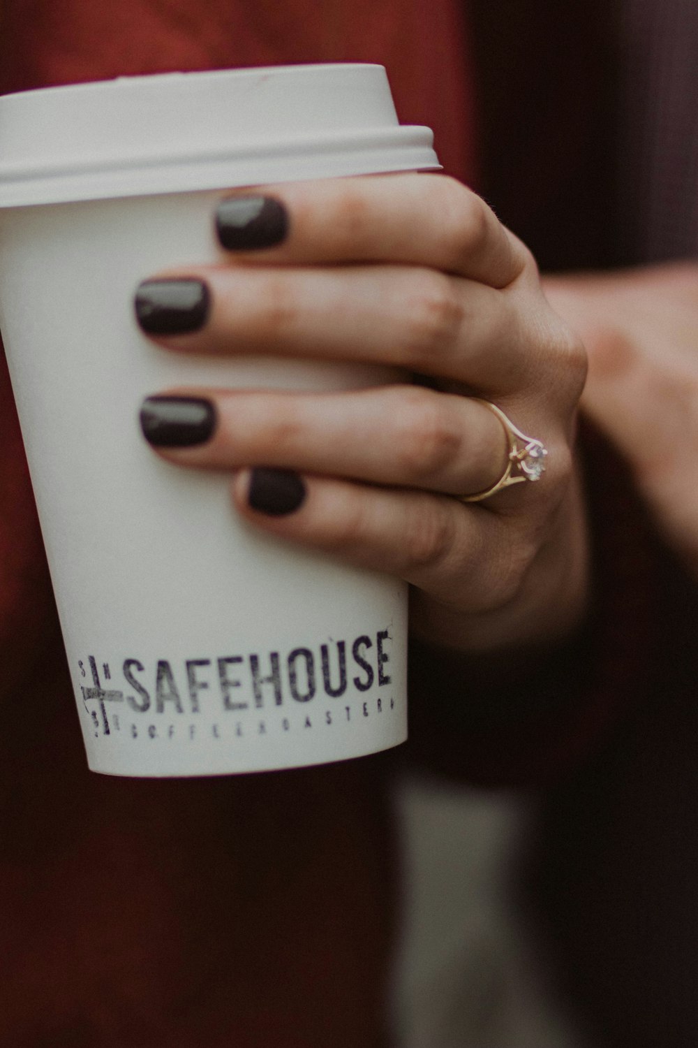 person holding a white Safehouse plastic cup