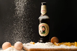 A chilled bottle of artisanal craft beer with condensation, set against a backdrop of pasta dishes