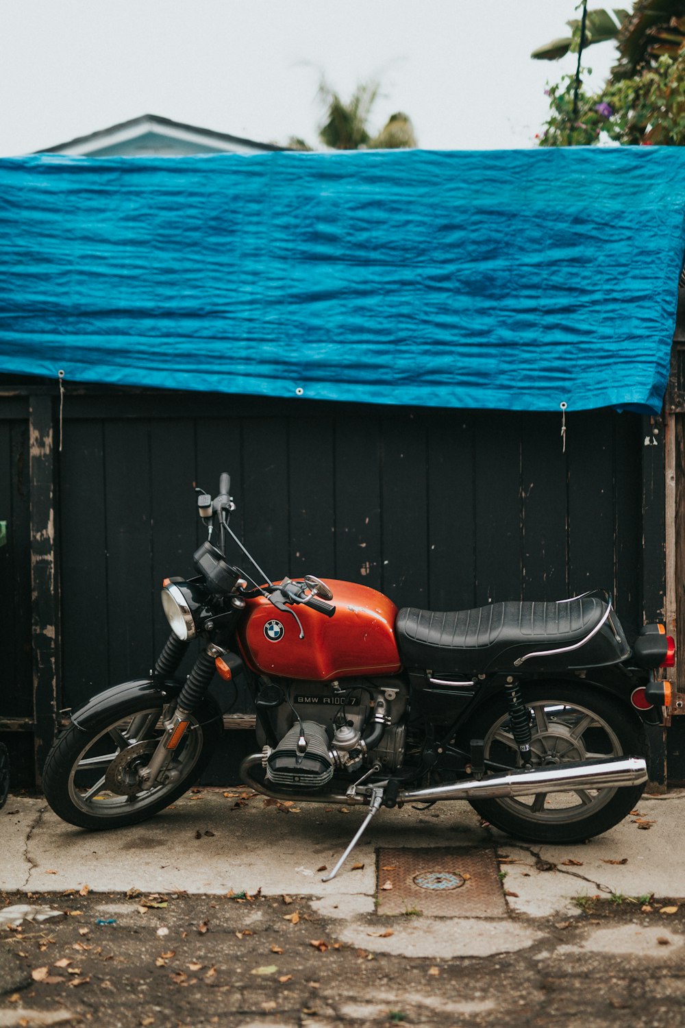 red, gray, and black standard motorcycle parked near black wall