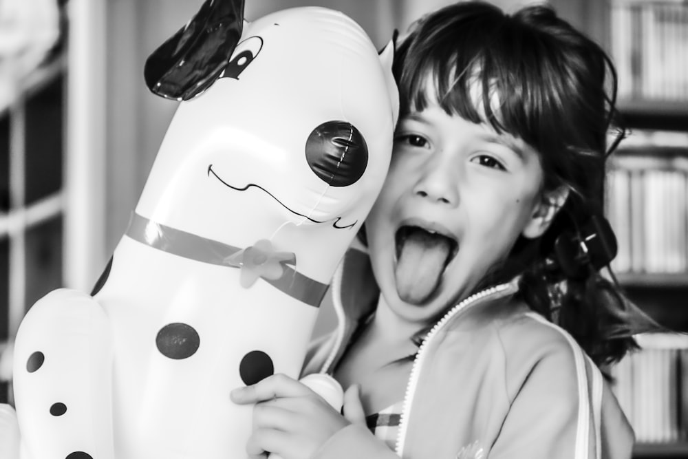 grayscale photography of girl making silly face while inflatable dalmatian balloon
