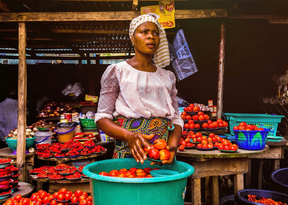 woman holding tomatoes near containers of tomatoes