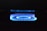 A blue flame from a gas stove burner is prominently displayed against a dark background. The flame forms a circular pattern with a soft, glowing appearance.