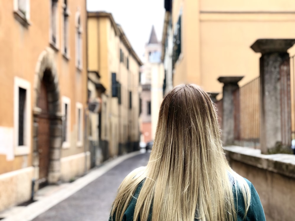 a woman with long blonde hair walking down a street