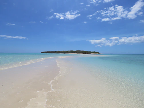 Playa de arena blanca y aguas turquesas en la isla de Bora Bora bajo un cielo despejado.