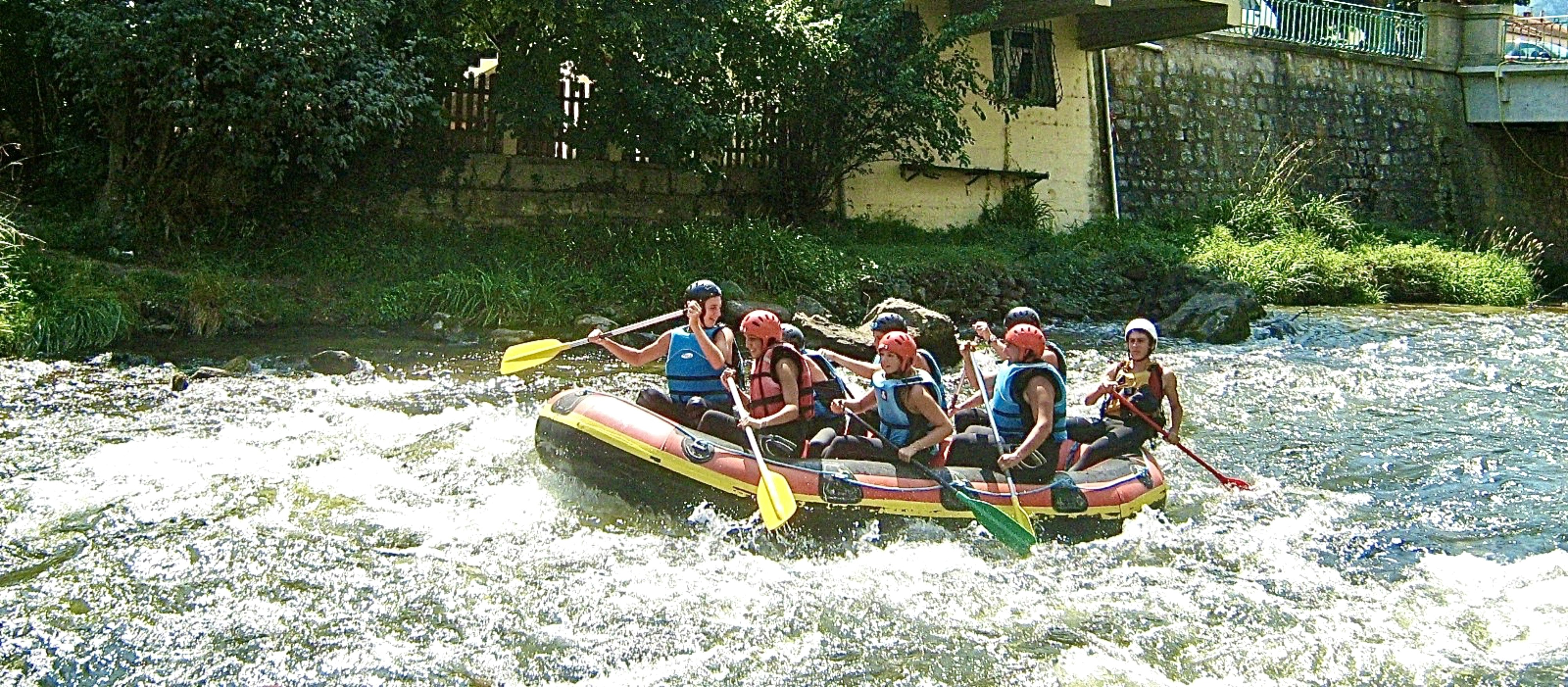 Group of people white water river rafting through rapids