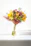 A vibrant bouquet of mixed flowers in bright colors arranged elegantly in a rustic vase.