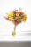 A vibrant bouquet of mixed flowers including roses and sunflowers in a rustic vase.