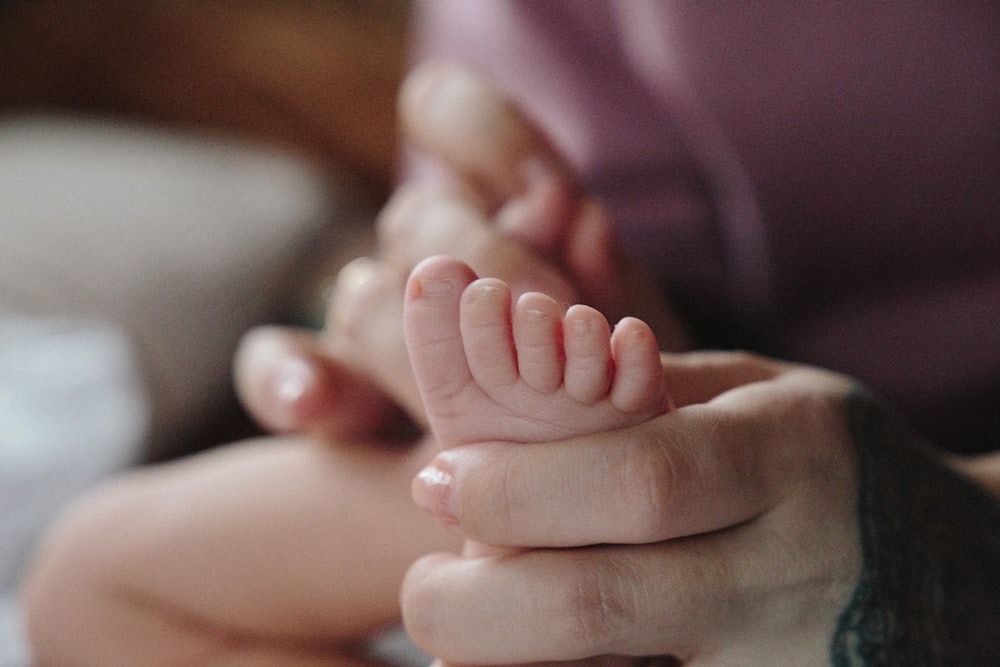 selective focus photography of person holding baby's feet