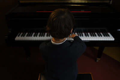 Young boy passionately playing piano on stage with orchestra in the background.