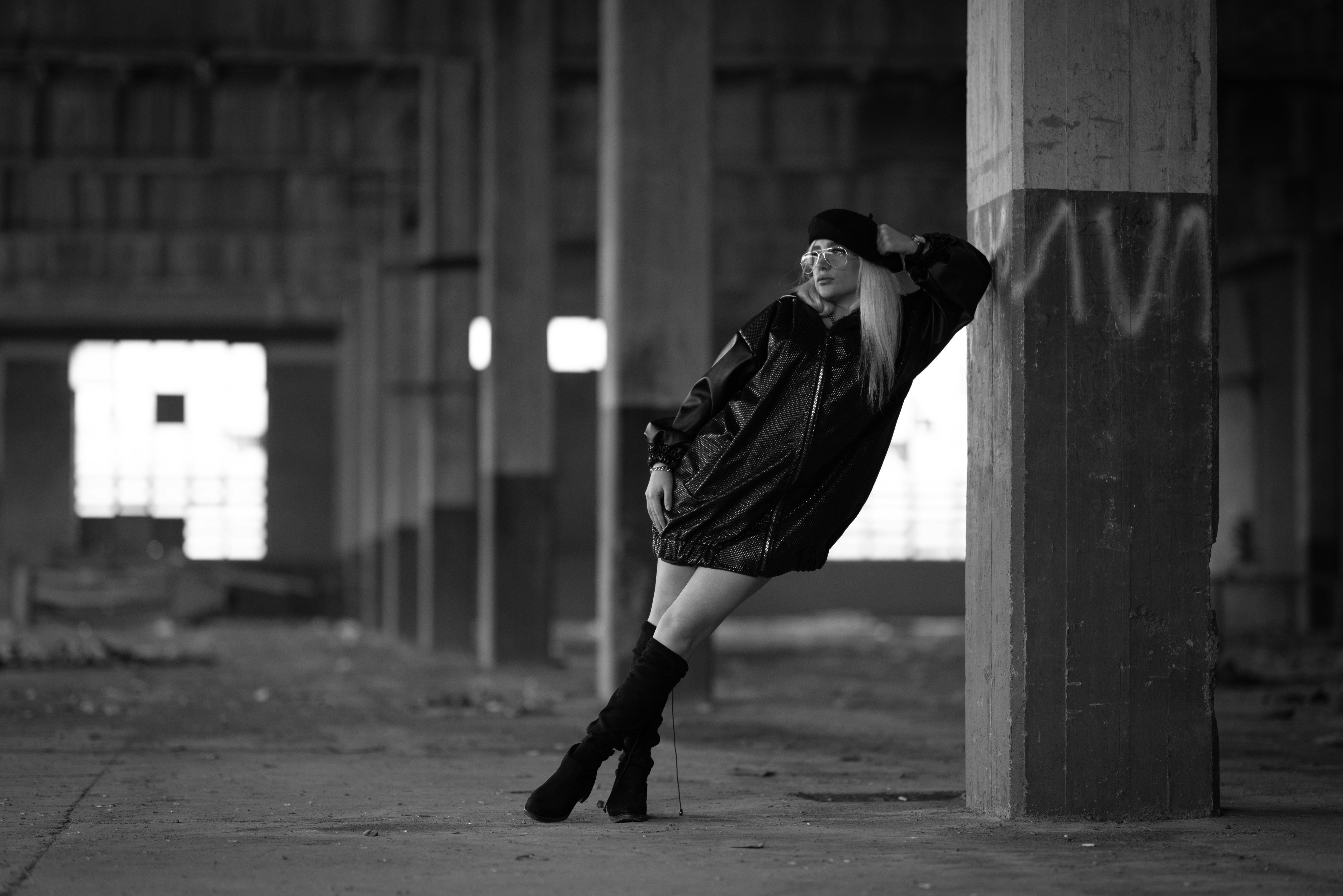 Grayscale photo of woman standing and leaning on concrete post photo