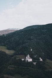 A whimsical fantasy castle nestled in lush green woods under a bright blue sky.