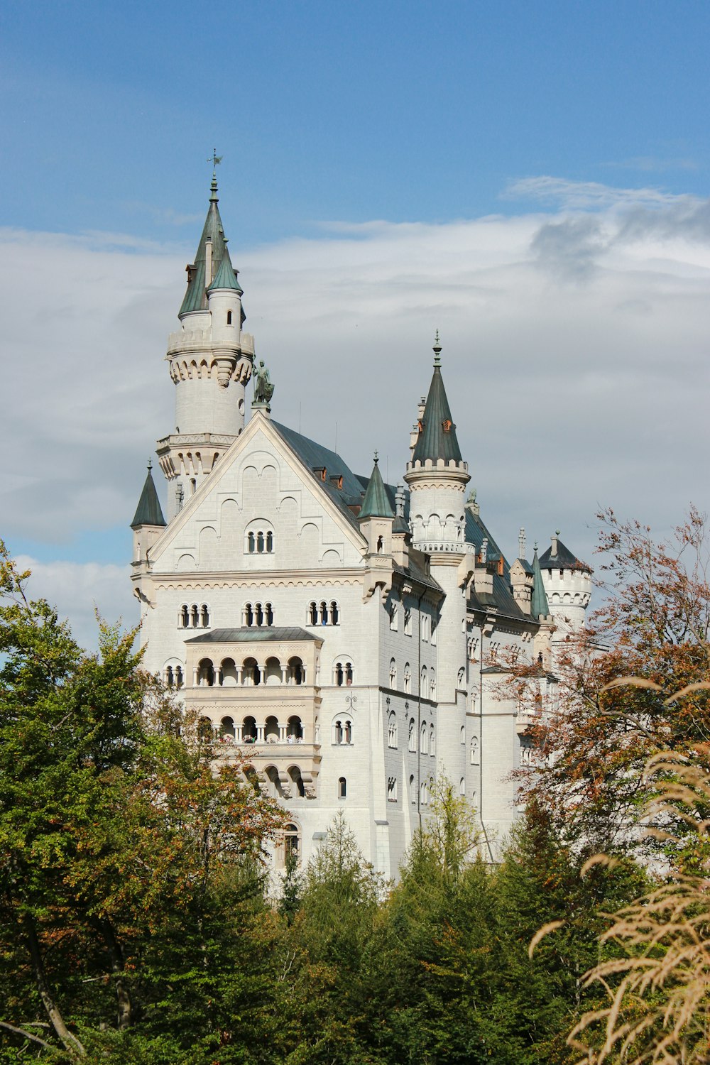 Weißes Schloss in der Nähe von Bäumen während des Tages