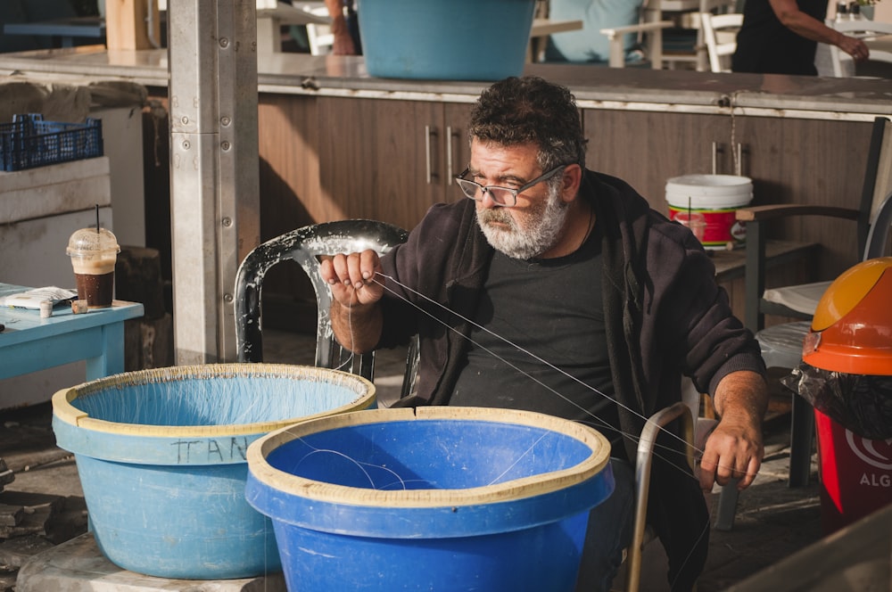 man sitting on chair near two blue pots
