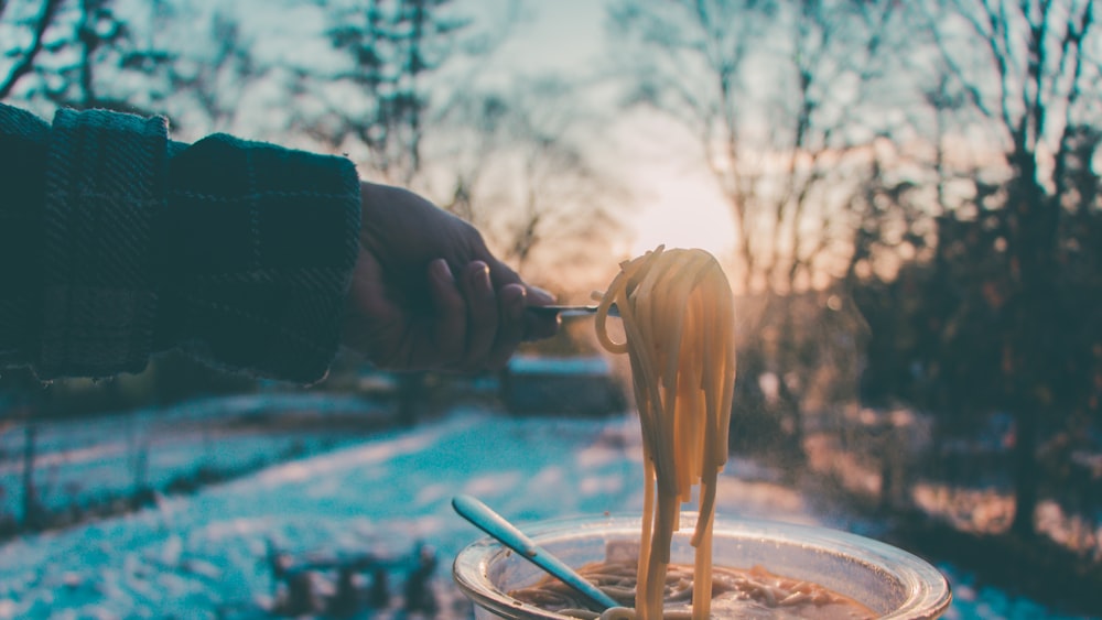 person holding spoon with noodles