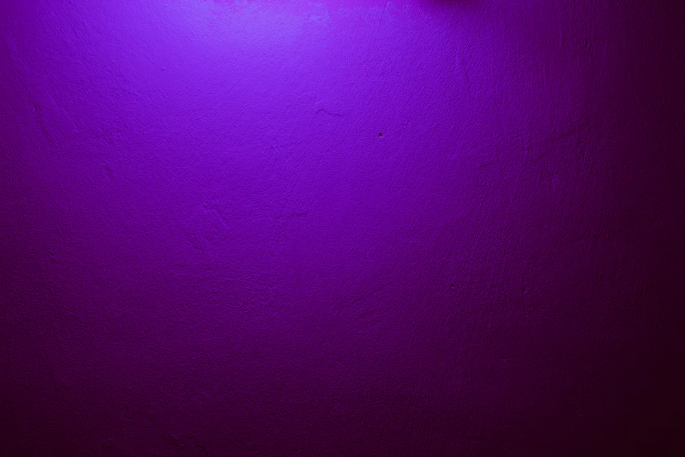 A textured purple wall lit from above.