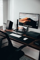 A minimalist desk setup with a laptop showing a paused video screen.