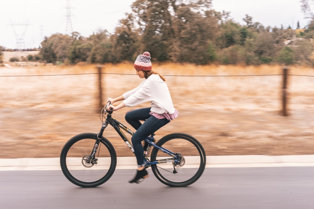 mulher que anda de bicicleta perto da árvore durante o dia