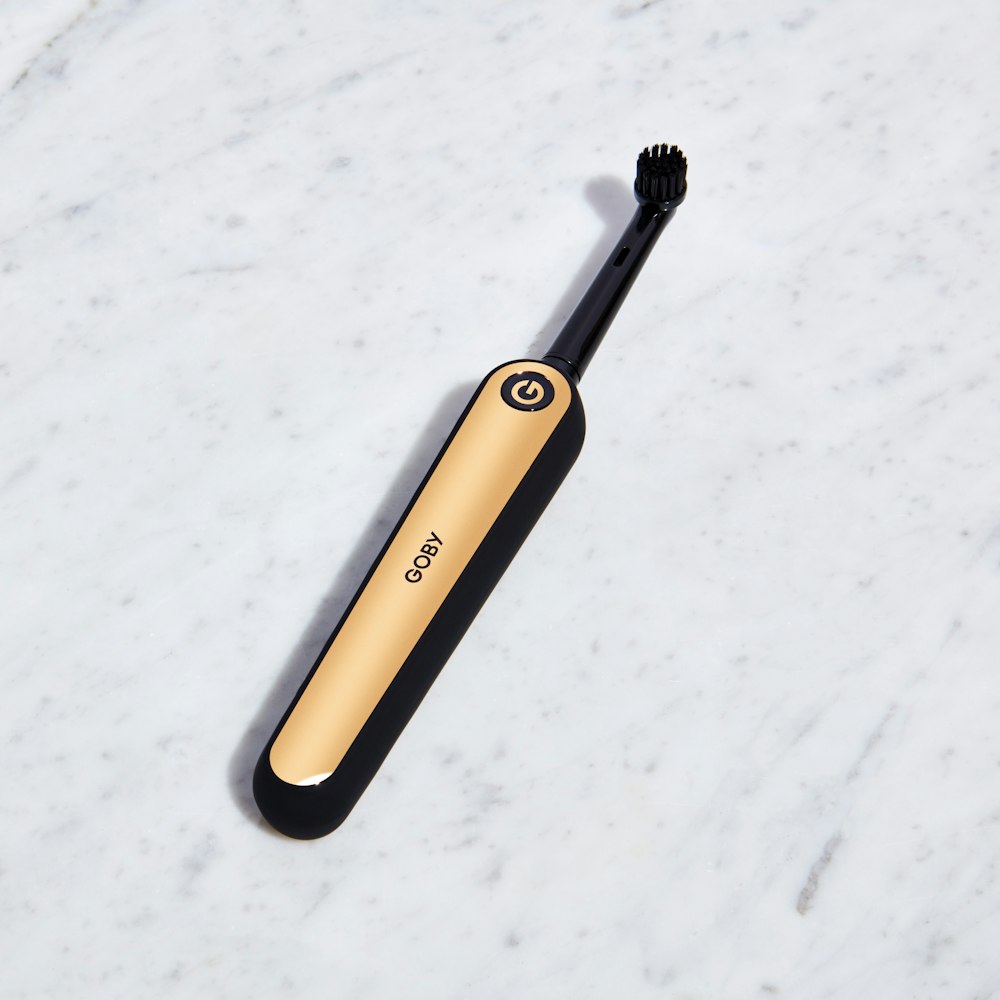 black and gold Goby electric toothbrush on white surface