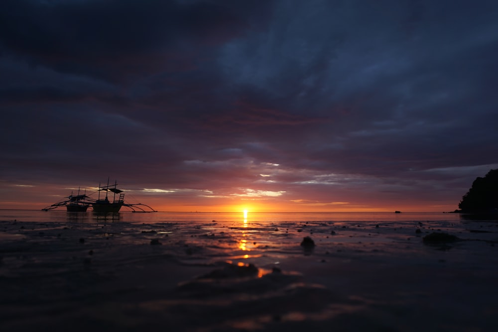 a boat sitting on top of a beach under a cloudy sky