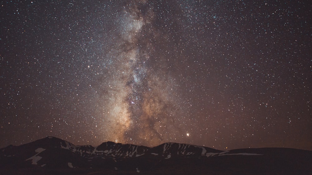 the night sky with stars above a mountain range