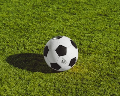 white and black soccer ball on grass field