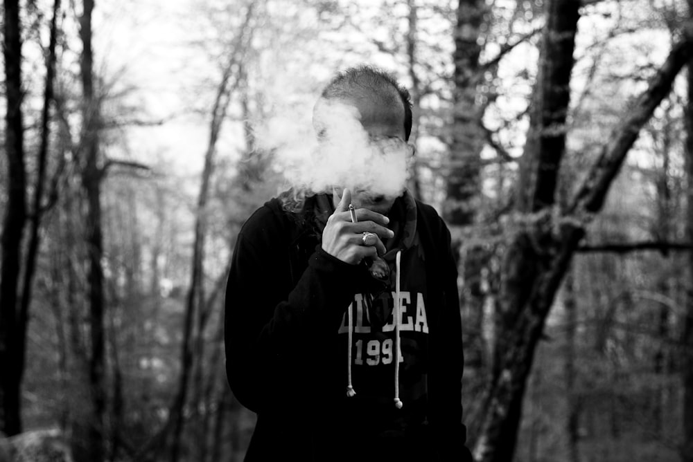 uomo che fuma vicino agli alberi durante il giorno