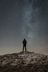 man standing on cliff duirng nighttime