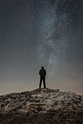 man standing on cliff duirng nighttime