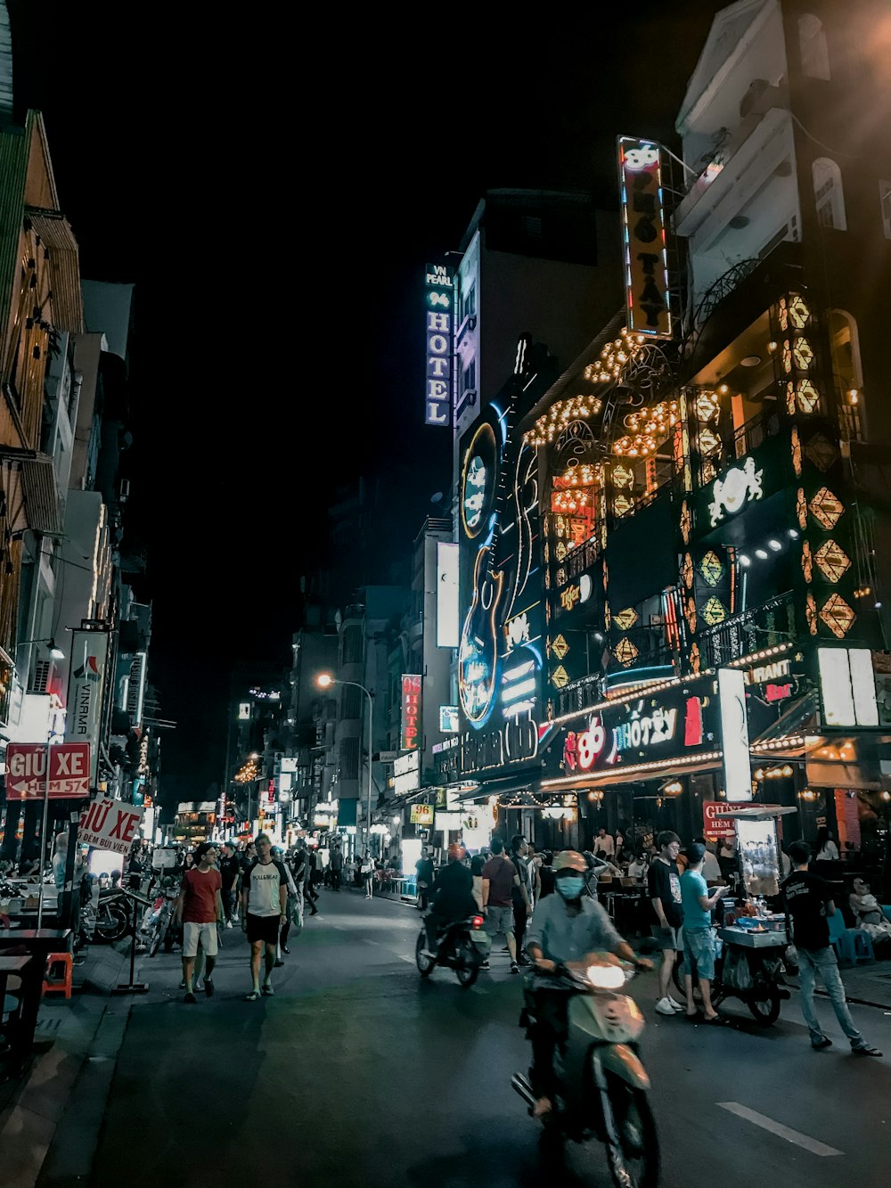 夜間に建物と建物の間の道路を歩く人々