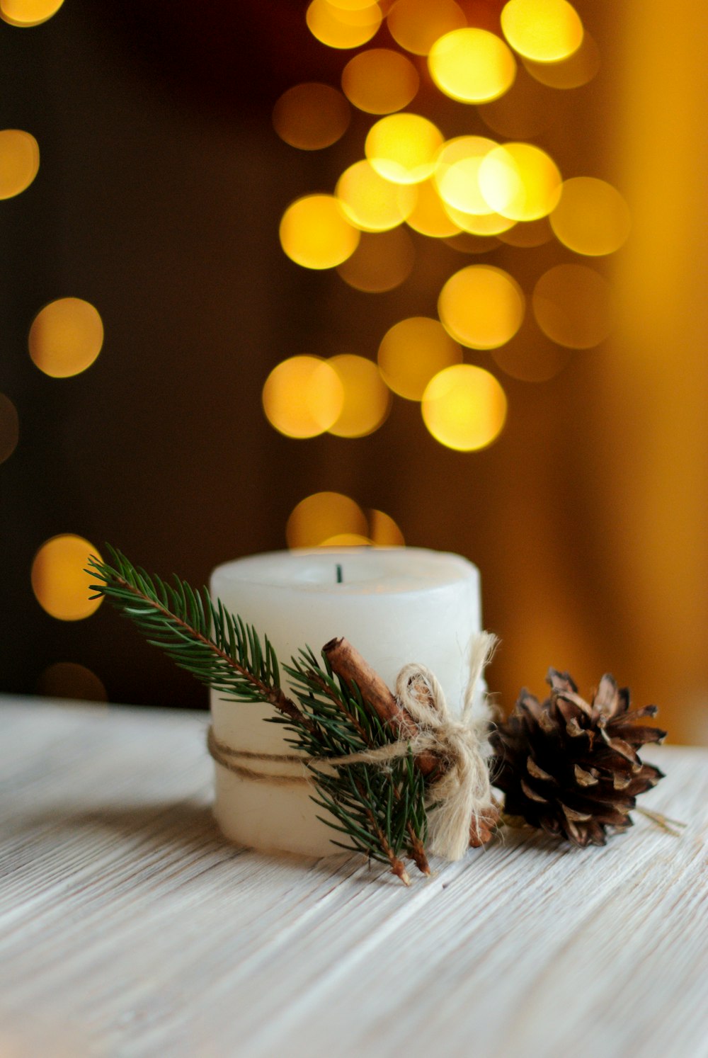 white pillar candle with pinecone
