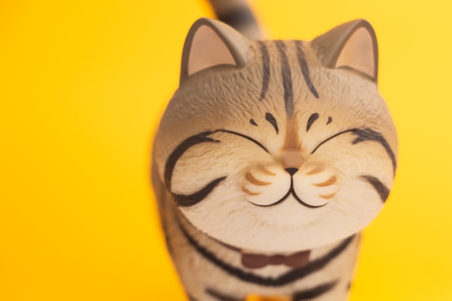 Close-up of a custom enamel pin shaped like a smiling cat with vibrant colors.