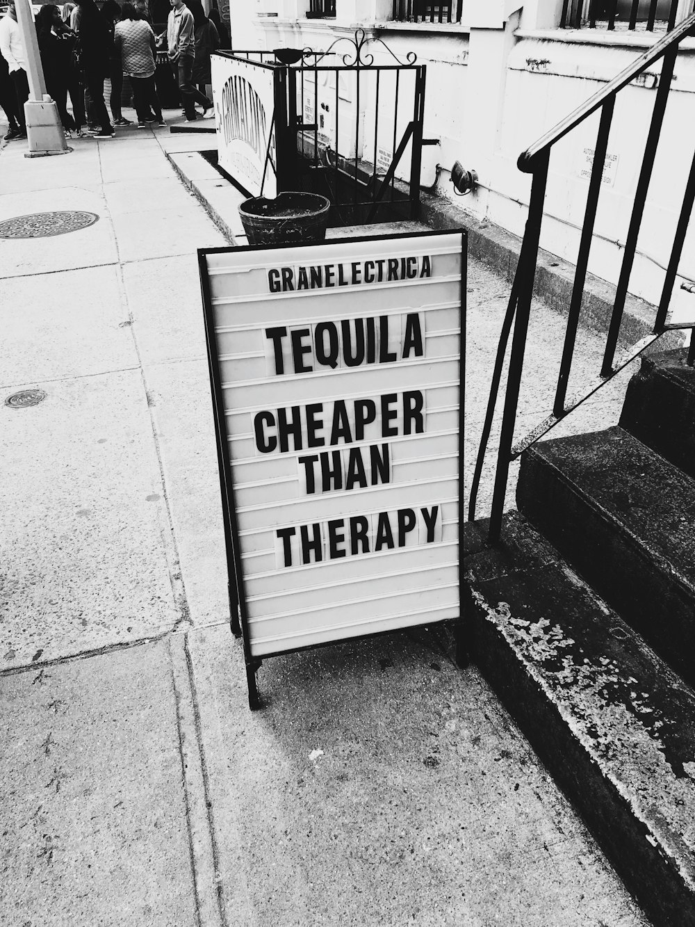 grayscale photo of tequila cheaper than and therapy signage