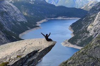 person sitting on rock near body of water during daytime