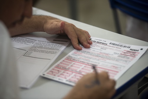 A student thoughtfully filling out a feedback form in a bright college classroom.