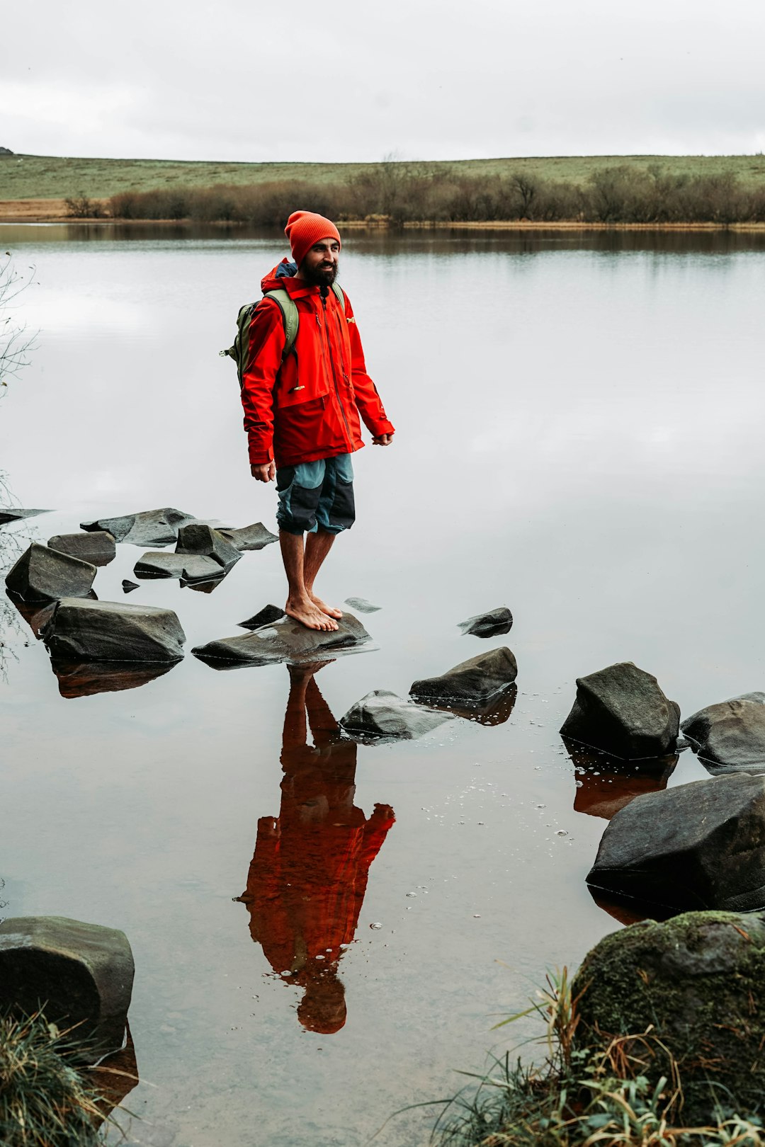 man standing on gray stone on calm water of river