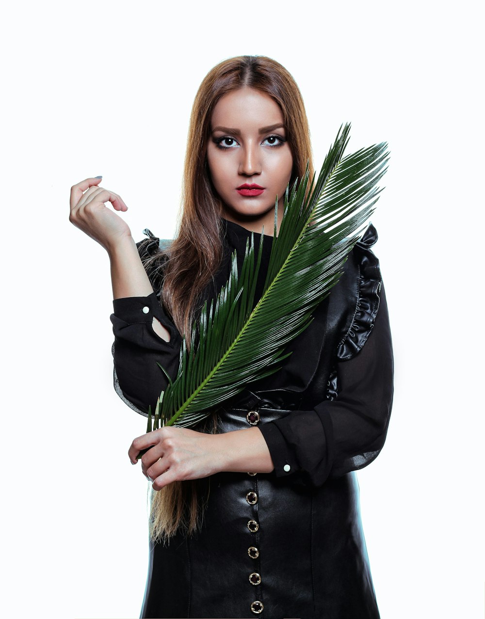 woman wearing black long-sleeved shirt holding green palm leaf