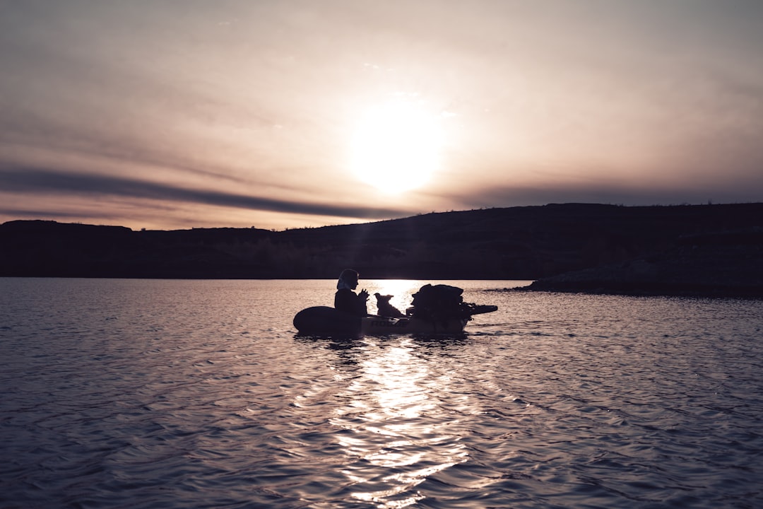 silhouette of 2 people riding boat on sea during sunset