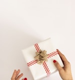 person holding white and red gift box