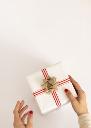 person holding white and red gift box