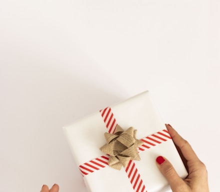 person holding white and red gift box