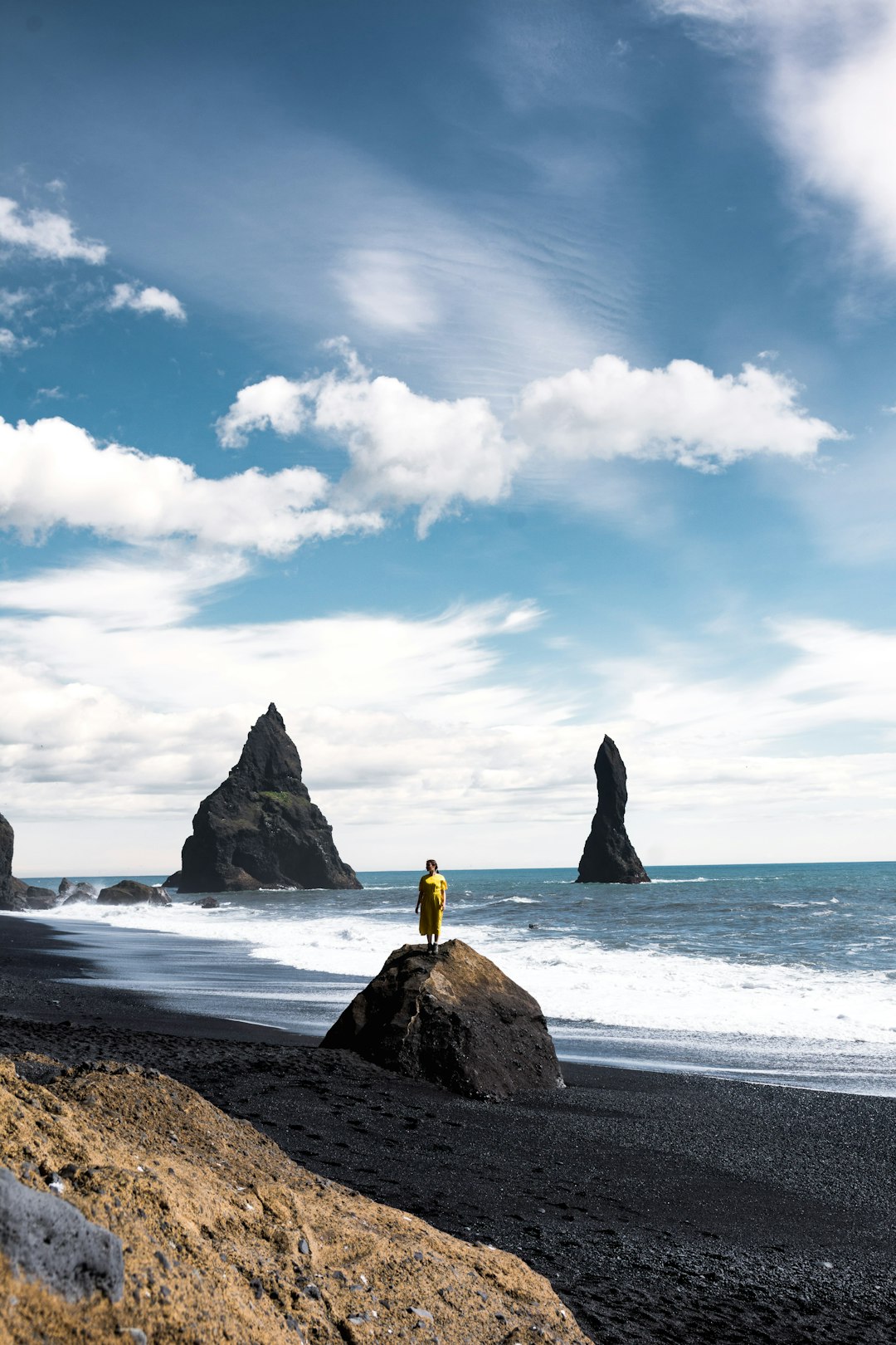 person wearing yellow jacket standing on seashore