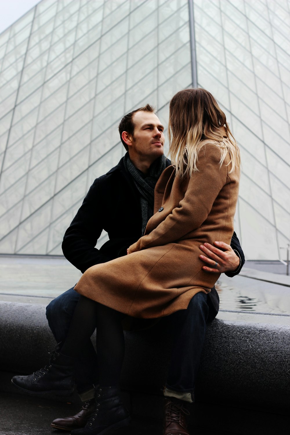 woman sitting on the lap of man sitting on the water fountain